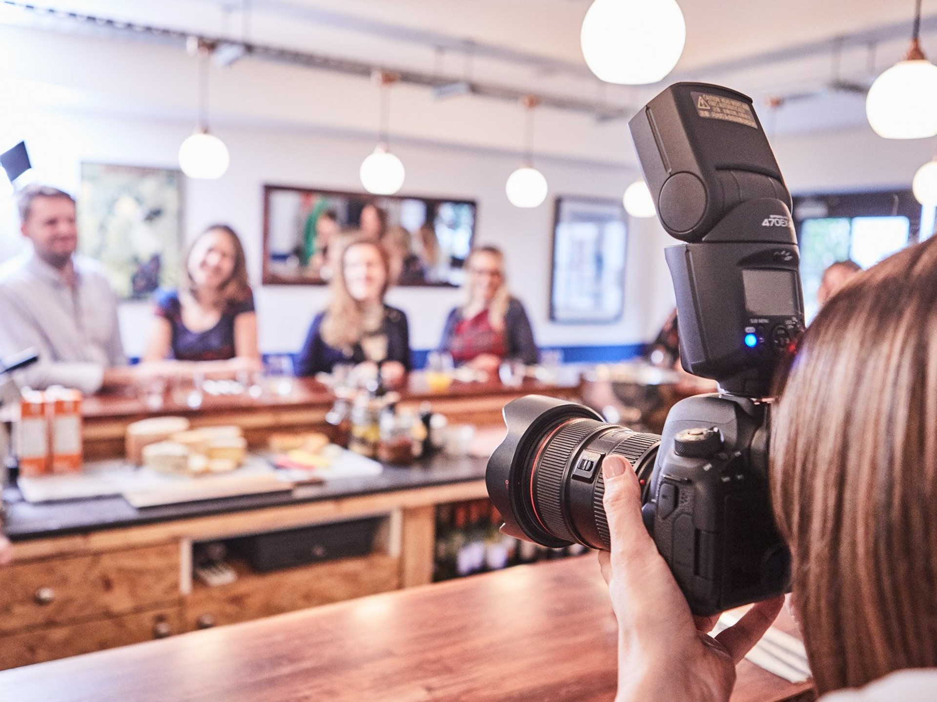 Female taking a group picture in a restaurant with a Canon 6D Mark II + Canon Speedlite 470EX-AI